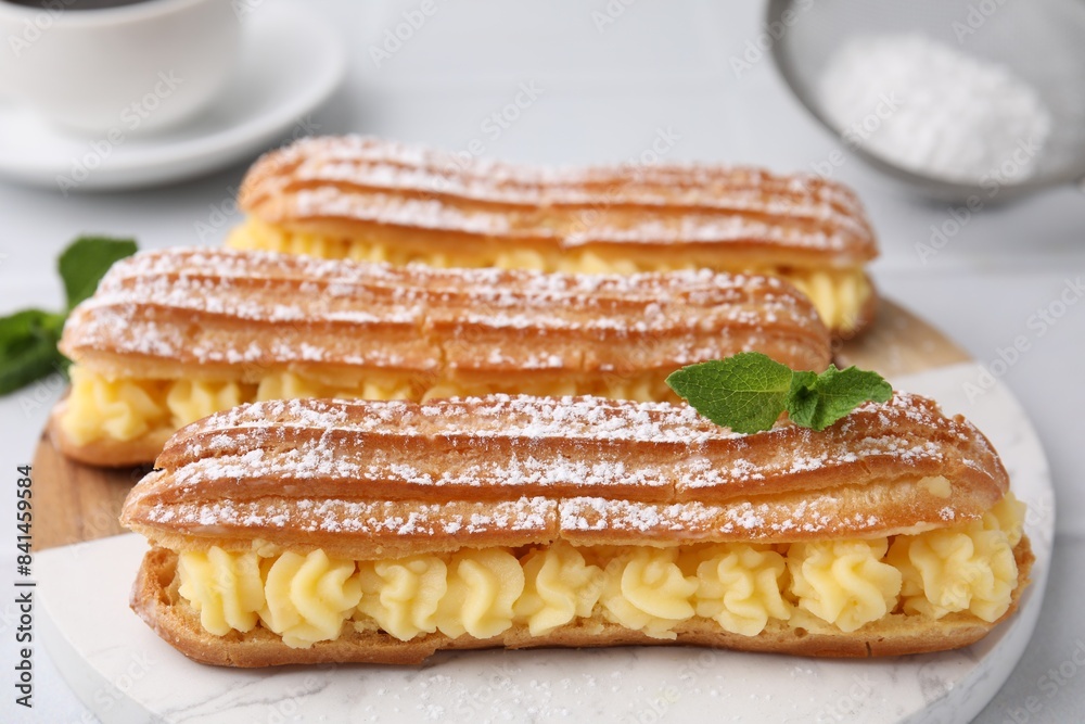Delicious eclairs filled with cream and mint on table, closeup Delicious eclairs filled with cream and mint on table, closeup
