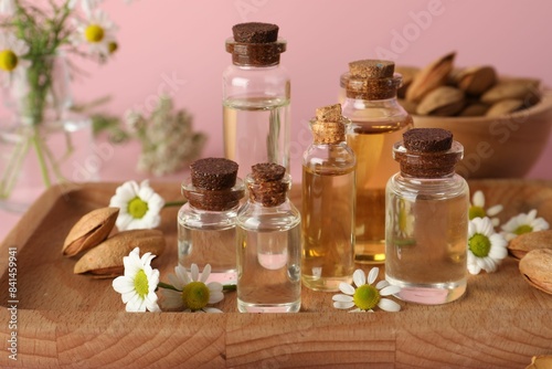 Aromatherapy. Different essential oils  flowers and almonds on pink background