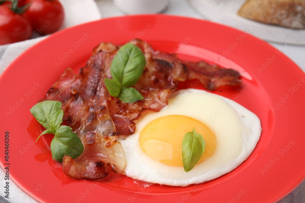 Fried egg, bacon and basil on table, closeup Fried egg, bacon and basil on table, closeup