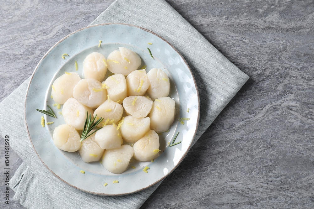 Raw scallops with lemon zest and rosemary on grey marble table, top view. Space for text Raw scallops with lemon zest and rosemary on grey marble table, top view. Space for text
