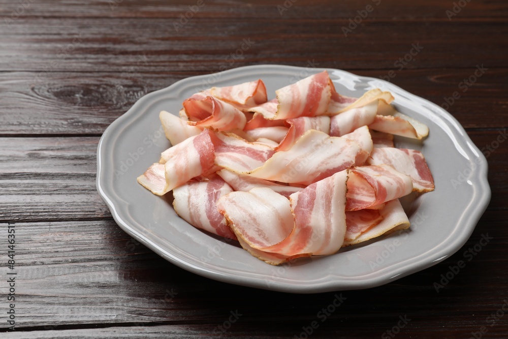 Slices of raw bacon on dark wooden table, closeup Slices of raw bacon on dark wooden table, closeup