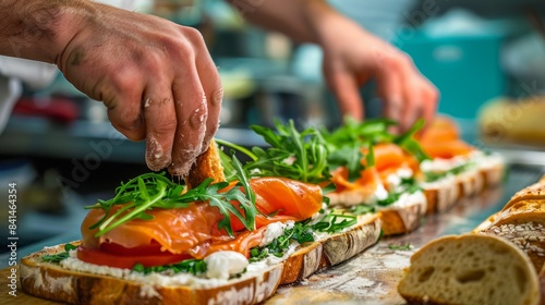 A chef assembling a gourmet sandwich with layers of smoked salmon, cream cheese, and arugula on freshly baked bread, showcasing the artistry of sandwich making