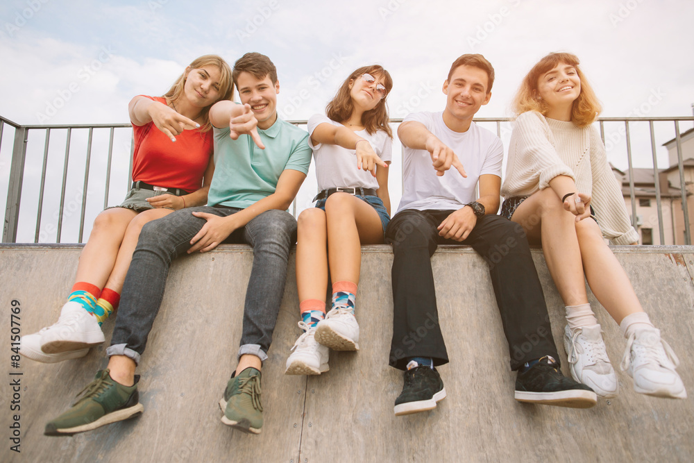 Obraz premium Summer holidays and teenage concept - group of smiling teenagers hanging out outside.