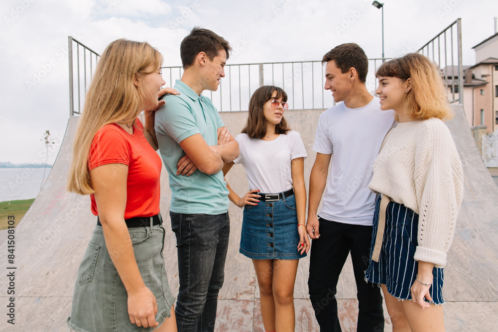 Fototapeta premium Summer holidays and teenage concept - group of smiling teenagers hanging out outside.