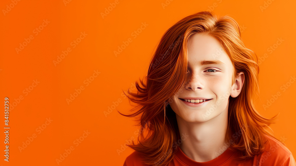 Portrait of a happy smiling red-haired, long haired confident teenage guy with perfect skin, orange background, banner. Portrait of a happy smiling red-haired, long haired confident teenage guy with perfect skin, orange background, banner.