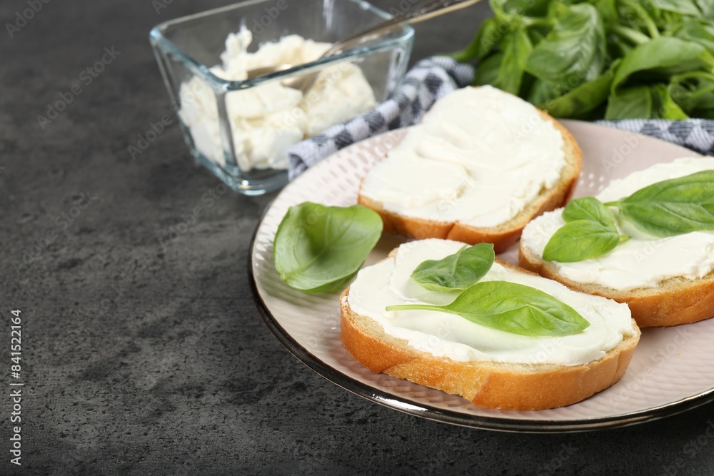 Delicious sandwiches with cream cheese and basil leaves on grey table. Space for text