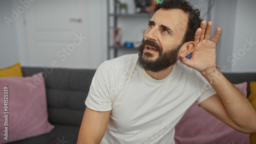 Bearded middle-aged man listens intently in a modern living room setting, embodying genteel composure.