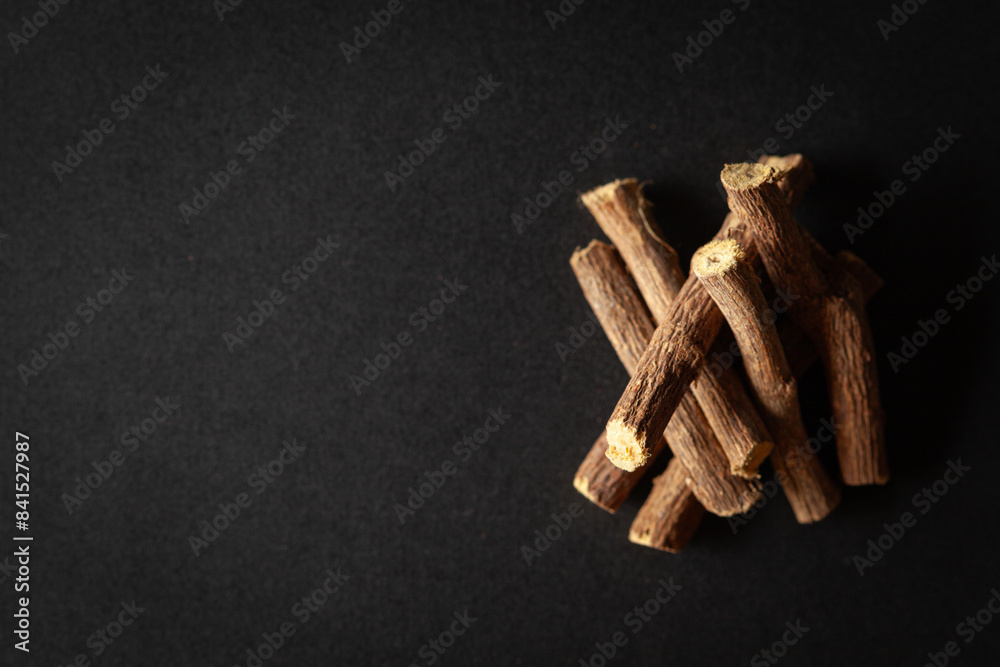 A pile of Dry Organic Liquorice or Mulethi (Glycyrrhiza glabra), isolated on a black background. Top view A pile of Dry Organic Liquorice or Mulethi (Glycyrrhiza glabra), isolated on a black background. Top view