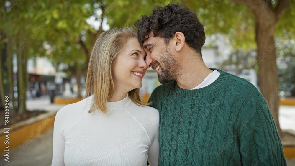 A smiling couple in a loving embrace outdoors in a city park, surrounded by greenery. A smiling couple in a loving embrace outdoors in a city park, surrounded by greenery.