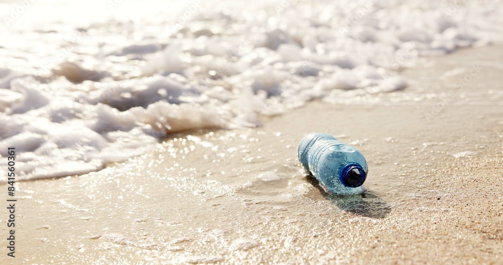 Obraz premium Beach, ocean and plastic bottle in sand for pollution, litter and trash in sea for global warming crisis. Nature, climate change and closeup of garbage in sea to reduce waste, recycling and cleaning