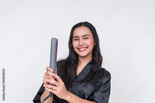 Woman in black silk bathrobe holding a flat iron for hair