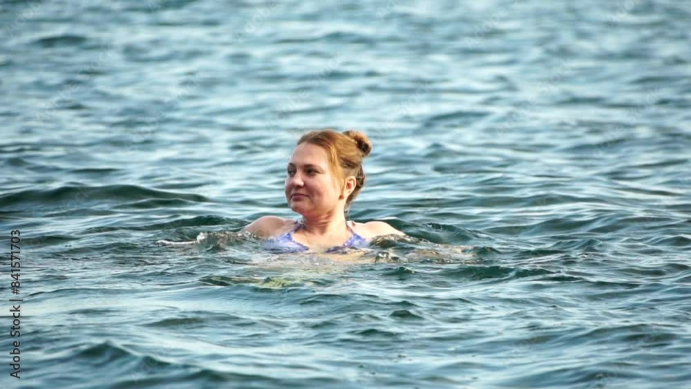 Woman swimming in calm sea at sunset, slow-motion, back view. Concept of body image and fitness, enjoying a serene beach. Happy woman with perfect fit body enjoys sea beach Woman swimming in calm sea at sunset, slow-motion, back view. Concept of body image and fitness, enjoying a serene beach. Happy woman with perfect fit body enjoys sea beach