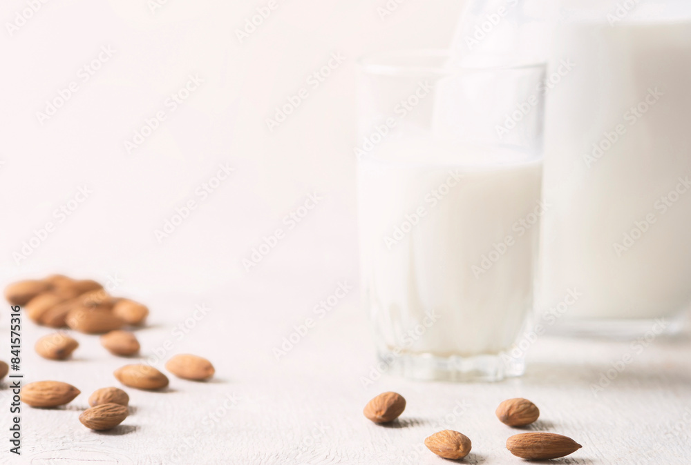 Alternative milk of almonds in a glass and glass jug on a wooden background. copy space Alternative milk of almonds in a glass and glass jug on a wooden background. copy space