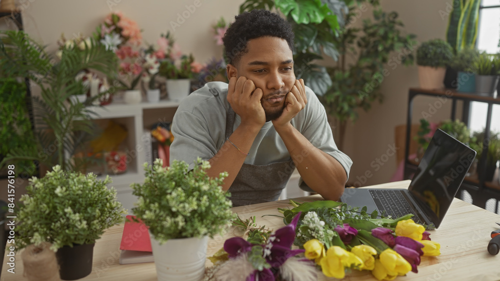 A contemplative african american man working amidst vibrant flowers inside a florist shop. A contemplative african american man working amidst vibrant flowers inside a florist shop.