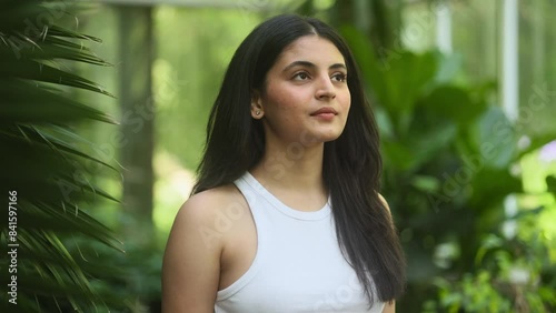 Portrait of calm young indian woman looking ahead and exhaling fresh air taking deep breath and reducing stress after hard day at park Serene dark haired female resting for peaceful mind outdoors
