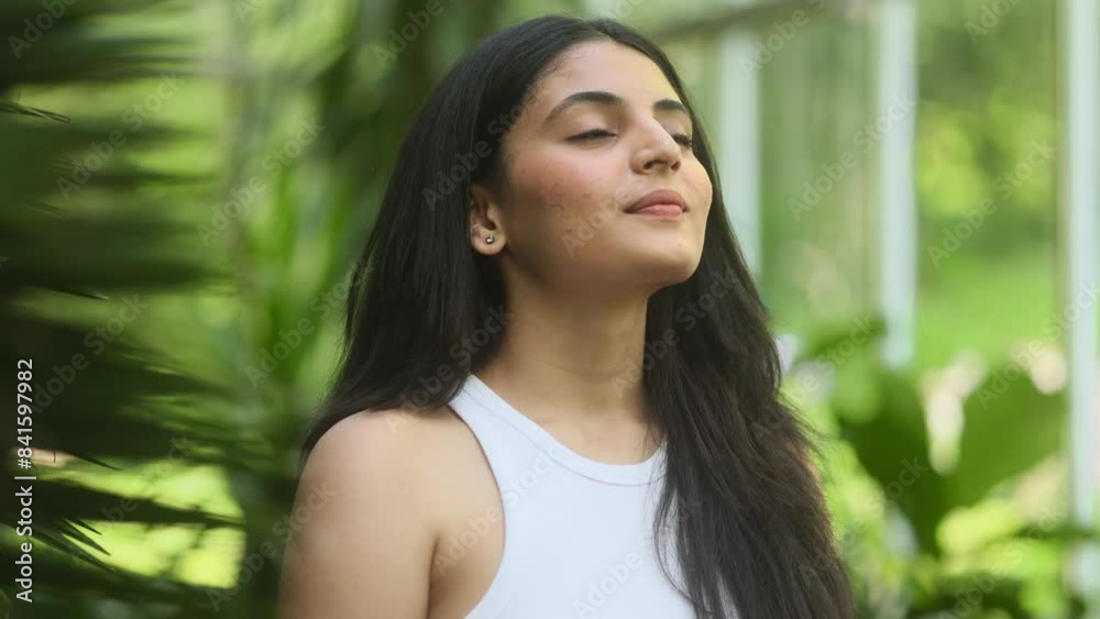 Portrait of calm young indian woman looking ahead and exhaling fresh air taking deep breath and reducing stress after hard day at park Serene dark haired female resting for peaceful mind outdoors Portrait of calm young indian woman looking ahead and exhaling fresh air taking deep breath and reducing stress after hard day at park Serene dark haired female resting for peaceful mind outdoors