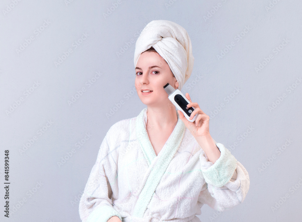 Beautiful woman in bathrobe massaging face Ultrasonic scraper  on green background