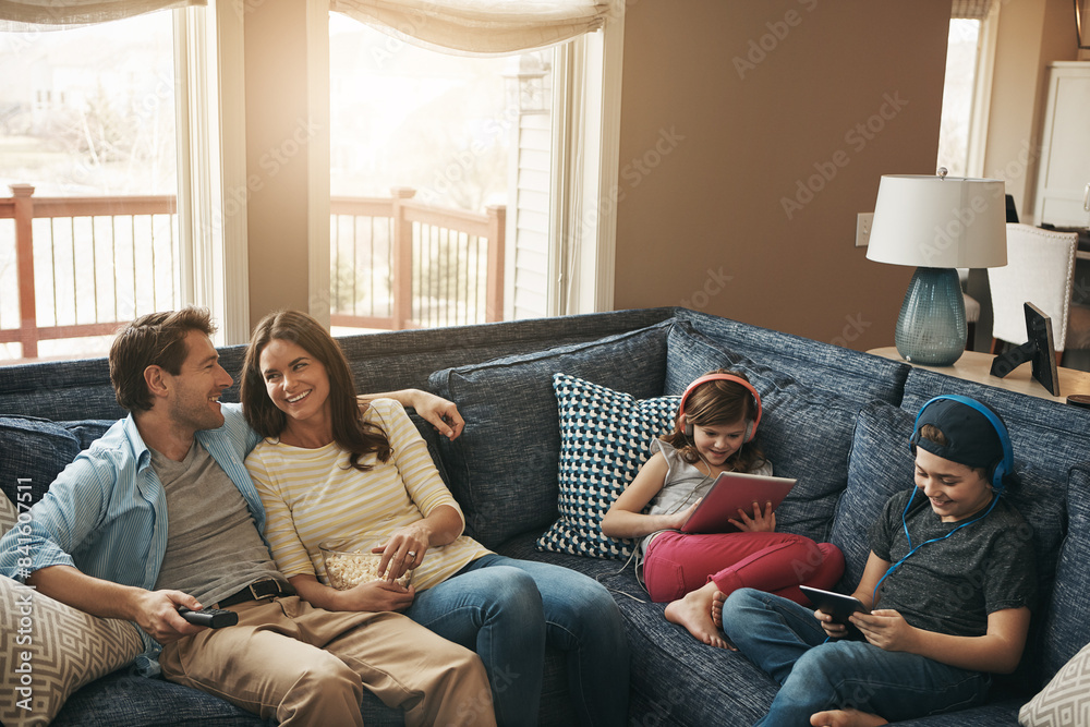 Family, children and parents on couch, watching tv or streaming on tablet with bonding in living room. Mother, father and kids with electronics, popcorn or movies to relax with show on sofa at house Family, children and parents on couch, watching tv or streaming on tablet with bonding in living room. Mother, father and kids with electronics, popcorn or movies to relax with show on sofa at house