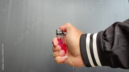 a hand lighting a gas lighter against a dark colored wall photo