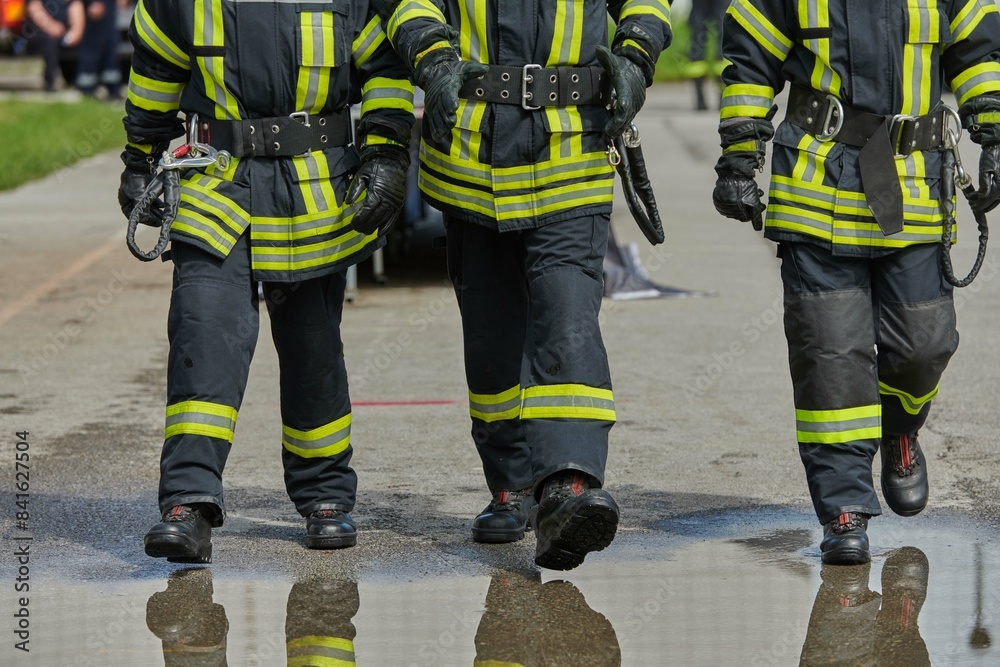 Fototapeta premium A team of confident and accomplished firefighters strides purposefully in their uniforms, exuding pride and satisfaction after successfully completing a challenging firefighting mission