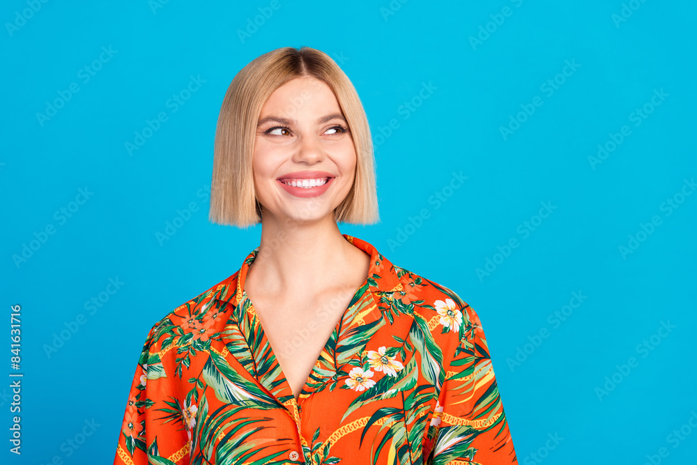 Photo of positive cute lovely girl wear stylish orange print clothes look empty space isolated on blue color background Photo of positive cute lovely girl wear stylish orange print clothes look empty space isolated on blue color background