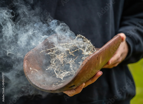 Australian Aboriginal smoking ceremony, human hands hold ritual dish at indigenous community event, joining to culture