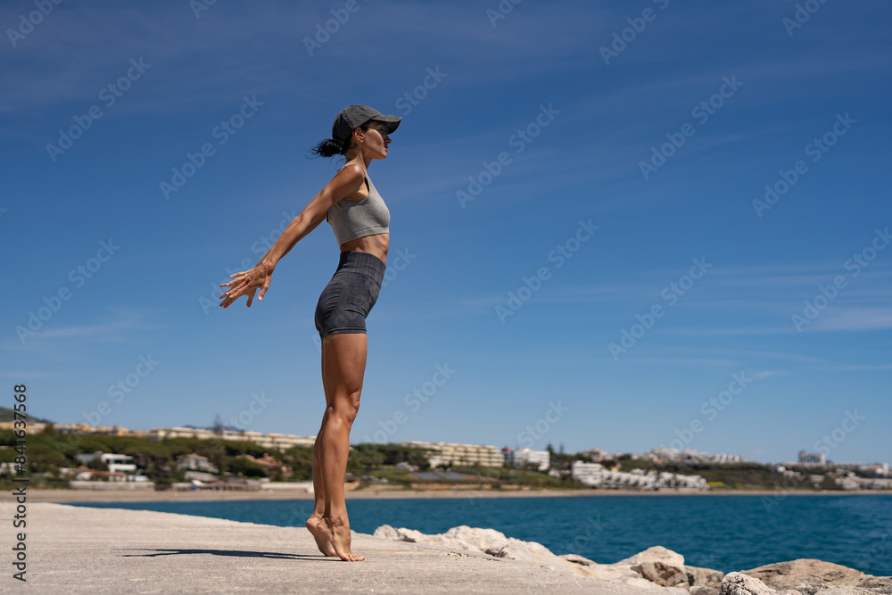 Sultry Brunette Athlete in Sportswear and Baseball Cap Training by the Sea Sultry Brunette Athlete in Sportswear and Baseball Cap Training by the Sea