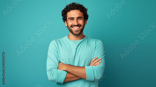 A cheerful millennial man posing with folded arms, isolated on white, smiling at the camera, set against a solid colored background