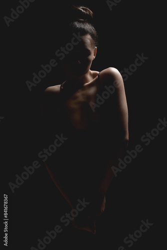 Woman silhouette in dark. Beautiful Brunette Girl over black background