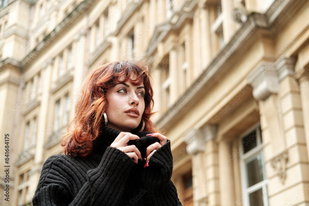 Low view of young female woman looking away in front of old building. Low view of young female woman looking away in front of old building.