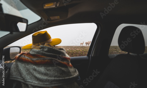 A man wearing a yellow hat is sitting in a car looking out the window, tourist in the peruvian andes
