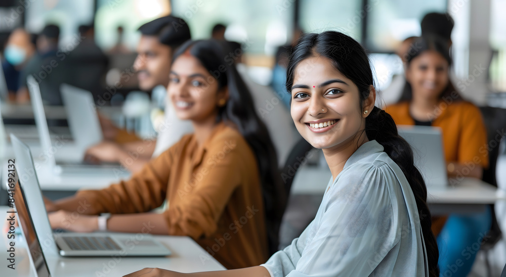 Diverse group of Indian office workers working on laptops in a modern open space, side view Diverse group of Indian office workers working on laptops in a modern open space, side view