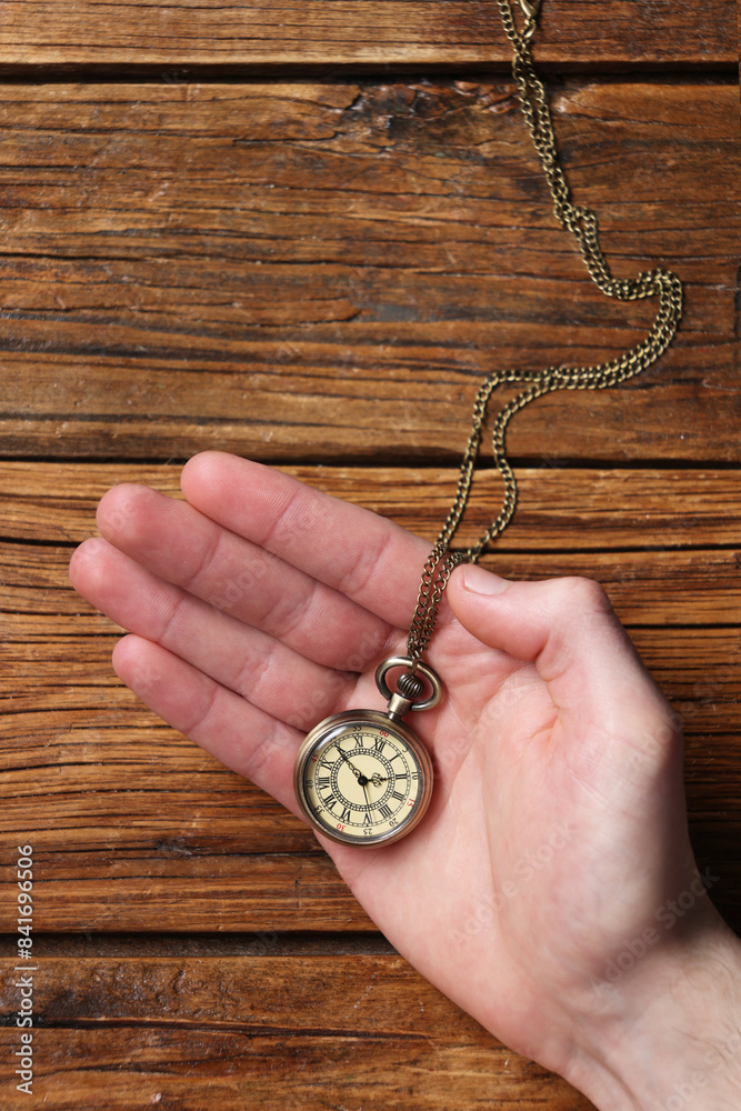 Man holding chain with elegant pocket watch at wooden table, top view Man holding chain with elegant pocket watch at wooden table, top view