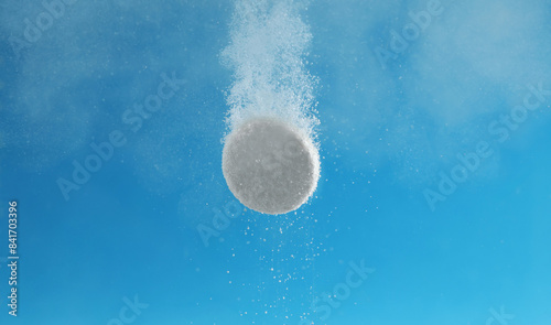Foto Effervescent pill dissolving in water on light blue background, closeup