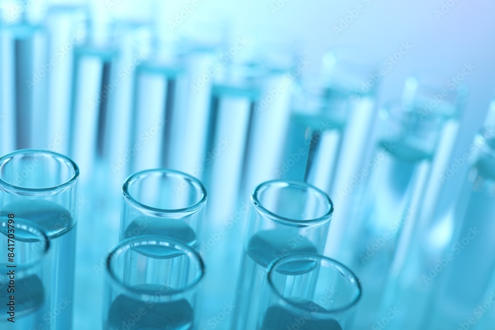 Many glass test tubes on light blue background, closeup Many glass test tubes on light blue background, closeup