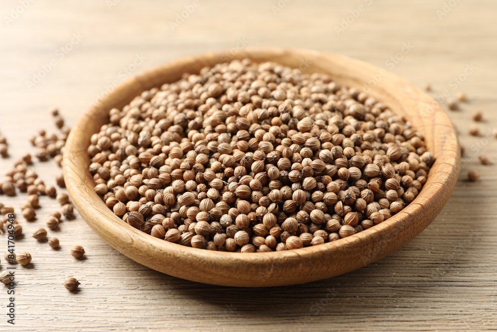 Dried coriander seeds in bowl on wooden table, closeup Dried coriander seeds in bowl on wooden table, closeup