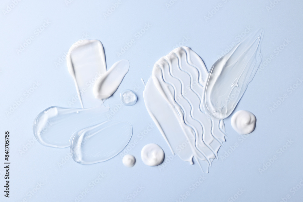 Fototapeta premium Samples of face cream on light blue background, top view