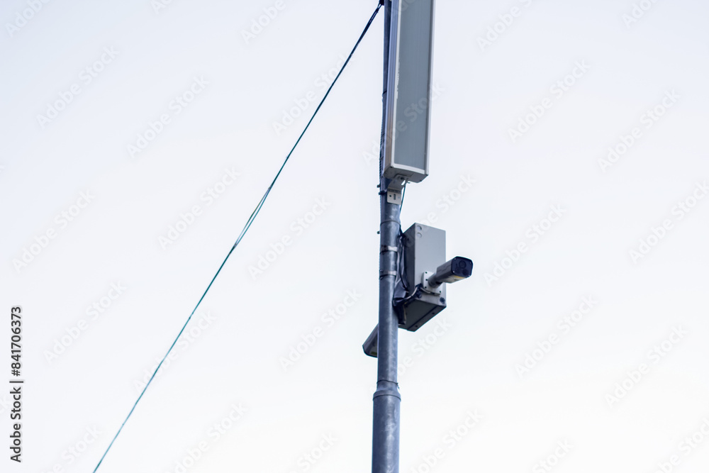 CCTV tool on grey sky background. CCTV camera monitoring a park for outdoor security. Surveillance camera watching over a park for safety CCTV tool on grey sky background. CCTV camera monitoring a park for outdoor security. Surveillance camera watching over a park for safety