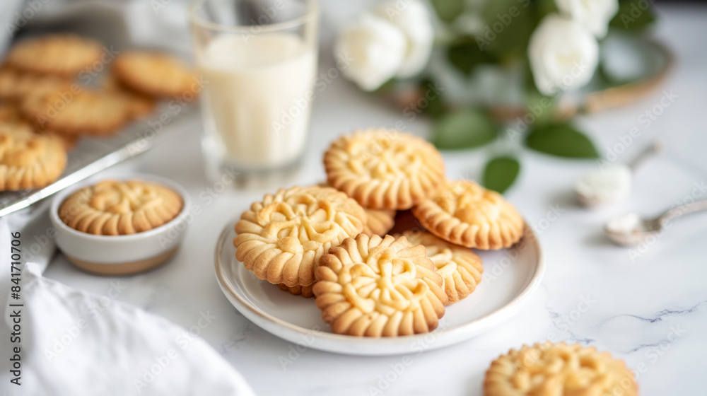 A plate of freshly baked shortbread cookies with a glass of milk on a white tabletop. A plate of freshly baked shortbread cookies with a glass of milk on a white tabletop.