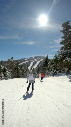 Vertical video teenagers downhill skiing in winter with family in Vermont, New England with fresh snow and sunshine