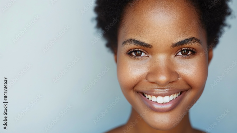 Close-up portrait of a smiling African American woman with glowing skin and a joyful expression.