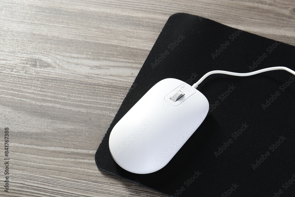 Wired mouse and mousepad on wooden table, space for text Wired mouse and mousepad on wooden table, space for text