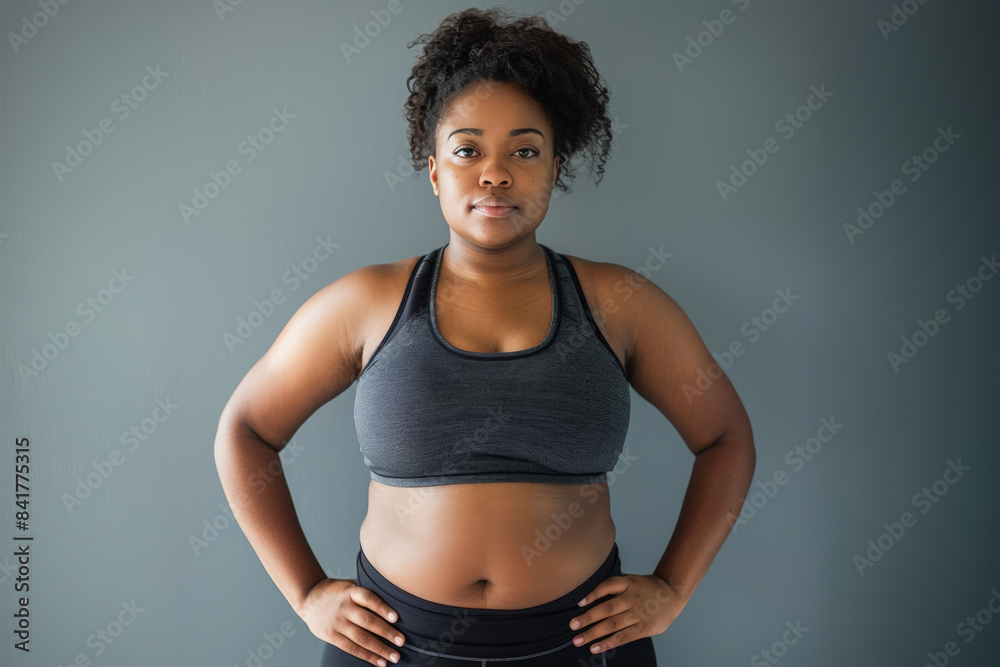 femme en surpoids en tenue de sport : legging et brassière, les mains sur les hanches