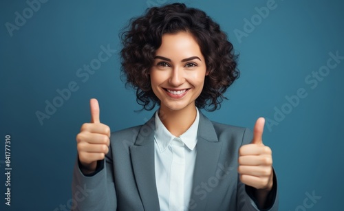 Confident Businesswoman Giving Thumbs Up in Front of Blue Background