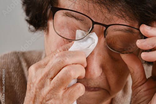 An old woman wiping tears from her eyes with a handkerchief. Shallow depth of field