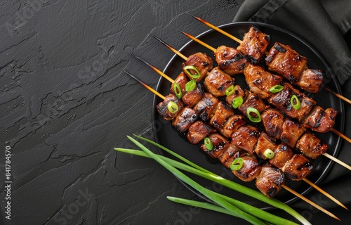 Grilled Meat Skewers With Green Onions and Cucumber Slices on Black Plate