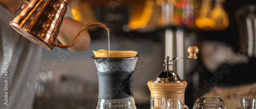 drip coffee, Barista making drip coffee by pouring spills hot water on coffee ground with prepare filter from copper pot to glass transparent chrome drip maker on wooden table in cafe shop