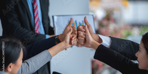 A group of business people giving thumbs up in a meeting.