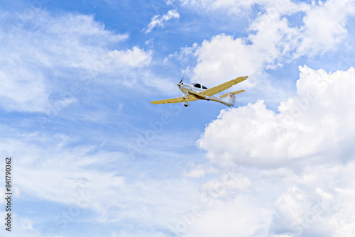 Single engine ultralight plane flying in the blue sky with white clouds