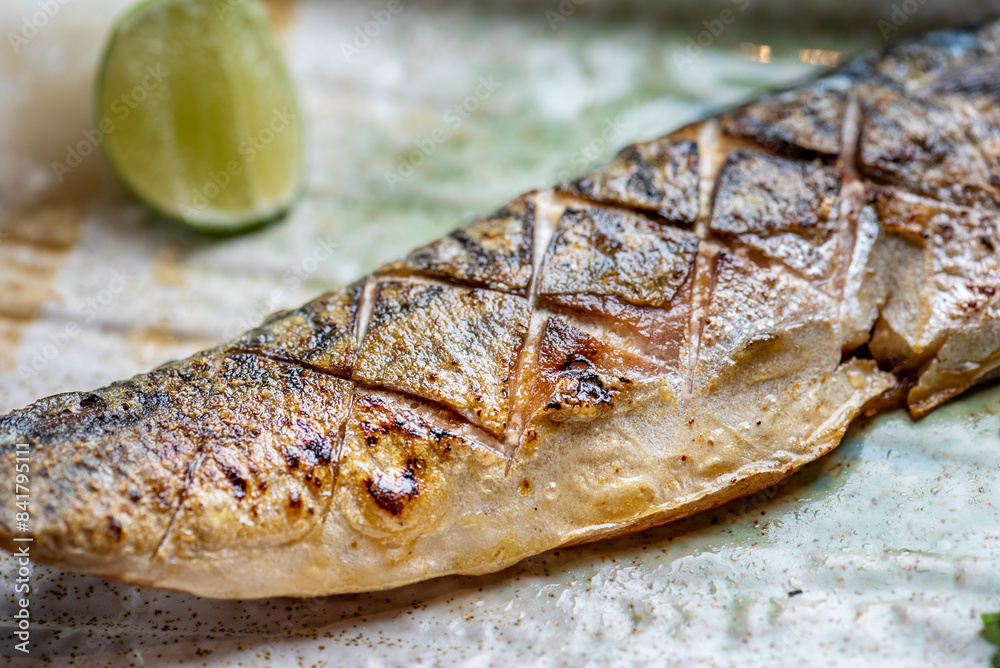 A close up of a grilled fish with a lime wedge on the side. A close up of a grilled fish with a lime wedge on the side.
